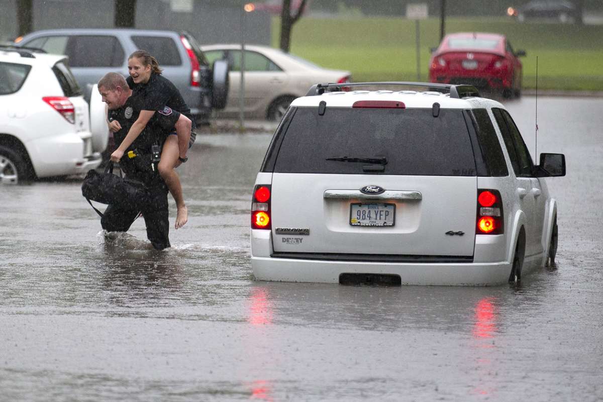 An ISU Police officer carries a stranded motorist from her vehicle through flood waters.